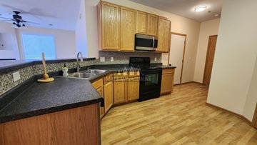 Rochester apartment for rent - A kitchen with wooden cabinets and a black counter top.