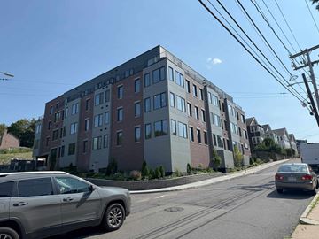 Boston apartment for rent - A modern apartment building with a car parked in front.