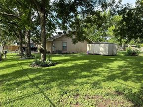 El Campo house for rent - A house with a brown roof and a brown fence is surrounded by trees.