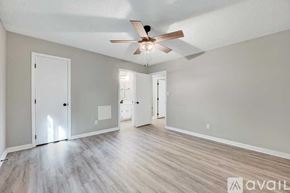Raleigh house for rent - A spacious room with a ceiling fan and light, hardwood floors, and white walls.