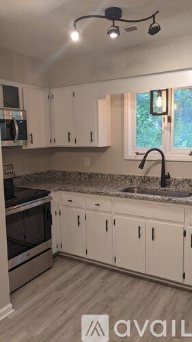 Raleigh house for rent - A kitchen with white cabinets and a granite countertop.