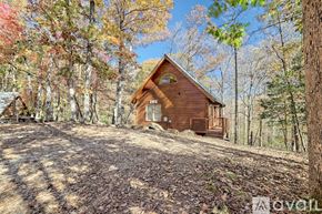 Demorest house for rent - A wooden cabin is surrounded by trees with autumn leaves.
