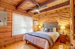 Demorest house for rent - A bedroom with wooden walls and a bed with a white comforter.