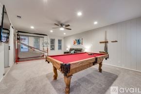 Dallas house for rent - A pool table is in the middle of a room with a ceiling fan.