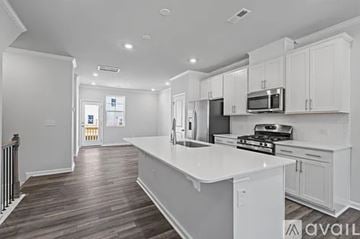 Clayton townhouse for rent - A modern kitchen with white cabinets and a wooden floor.