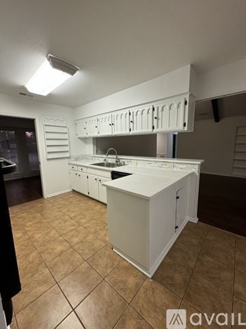Castle Hills house for rent - A kitchen with white cabinets and brown tiled flooring.