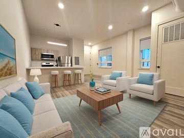 East Orange apartment for rent - A living room with a white couch, a coffee table, and a painting on the wall.