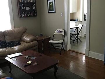Raleigh house for rent - A living room with a brown leather couch, a wooden coffee table, and a chair with the word "Gators" on it.