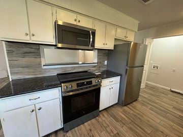 Bay City house for rent - A kitchen with white cabinets and black countertops.