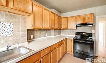 Frederick apartment for rent - A kitchen with wooden cabinets and a black stove top oven.