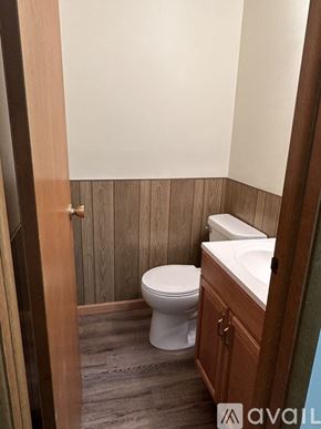 Pekin house for rent - A white toilet sits in a bathroom with wood paneling.