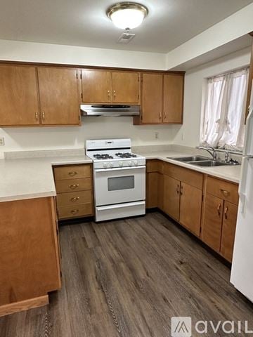 Pekin house for rent - A kitchen with wooden cabinets and a white stove top oven.