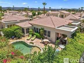 La Quinta house for rent - A house with a pool surrounded by greenery and palm trees.