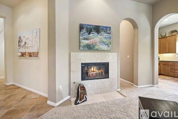 La Quinta house for rent - A living room with a fireplace and a painting of a forest scene on the wall.