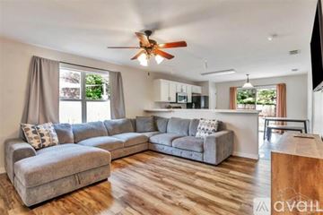 Gulf Breeze house for rent - A living room with a grey sectional sofa and a wooden floor.