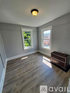 Newburgh apartment for rent - A room with wooden flooring and a window overlooking a red building.
