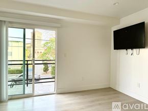 Los Angeles apartment for rent - A spacious room with a flat screen TV mounted on the wall and sliding glass doors leading to a balcony.