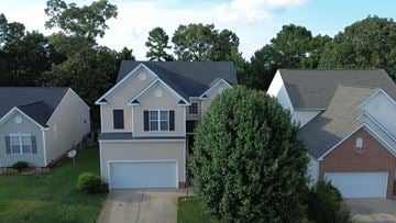 Raleigh house for rent - A house with a garage is surrounded by other houses and trees.