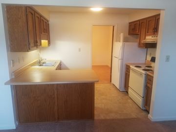 Richmond apartment for rent - A kitchen with wooden cabinets and a white refrigerator.
