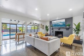 Los Angeles house for rent - A living room with a grey couch, yellow chair, and a fireplace.