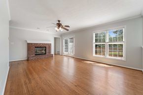 Jacksonville house for rent - A living room with a fireplace and a ceiling fan.