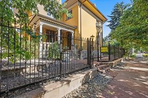 Denver apartment for rent - A yellow house with a black fence and a stone pathway leading to the front door.