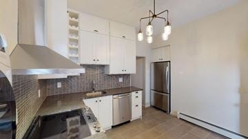 Denver apartment for rent - A modern kitchen with white cabinets and a stainless steel refrigerator.
