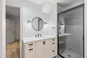 Denver apartment for rent - A bathroom with a white countertop and a round mirror above it.
