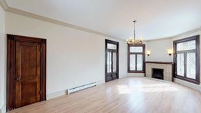 Denver apartment for rent - A large empty room with a fireplace and a chandelier.