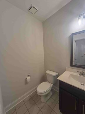 Clarksville house for rent - A white toilet sits next to a sink in a bathroom.