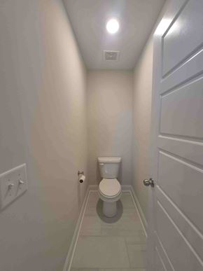 Clarksville house for rent - A white toilet in a narrow bathroom with a door on the right.
