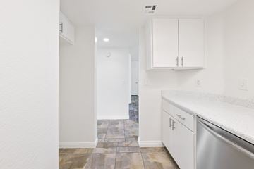 Riverside apartment for rent - A kitchen with white cabinets and a tiled floor.