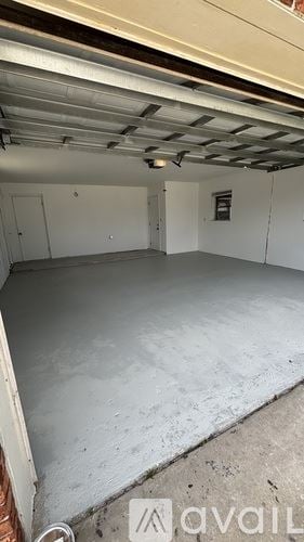 Cocoa house for rent - A spacious garage with a concrete floor and a white ceiling with visible beams.