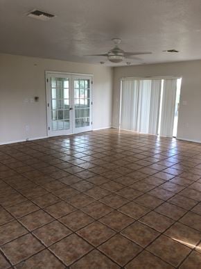 Cocoa house for rent - A room with a brown tile floor and a ceiling fan.