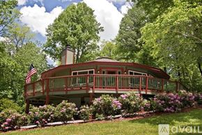 Sky Valley house for rent - A house with a red roof and a balcony surrounded by green trees and bushes.