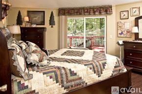 Sky Valley house for rent - A bedroom with a large bed and a view of a deck outside the window.