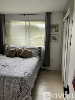 Laconia townhouse for rent - A bedroom with a bed and a window with blinds.