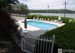 Laconia townhouse for rent - A pool surrounded by white chairs and a white fence.