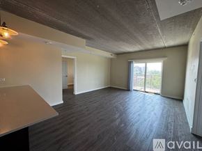 Chicago apartment for rent - A spacious room with a concrete ceiling and a large window.