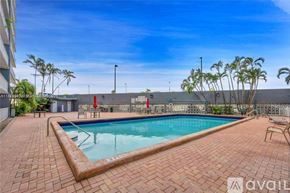 Miami apartment for rent - A pool surrounded by a brick patio and palm trees.