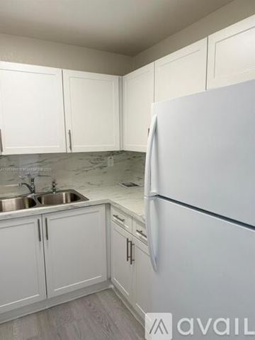 Miami apartment for rent - A kitchen with white cabinets and a white fridge.
