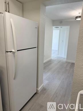 Miami apartment for rent - A white fridge in a room with wooden flooring.
