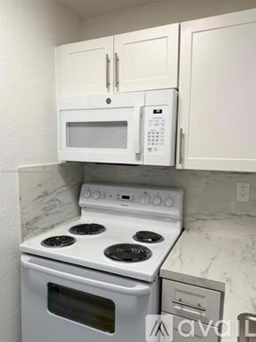 Miami apartment for rent - A white microwave oven is mounted above a white stove in a kitchen.