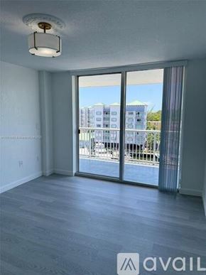 Miami apartment for rent - A room with a sliding glass door leading to a balcony with a view of a building.
