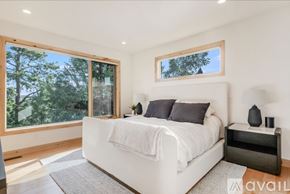 Kalispell house for rent - A bedroom with a large bed and a window overlooking trees.