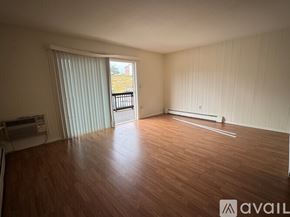 Seymour condo for rent - A room with wooden flooring and a sliding glass door leading to a balcony.