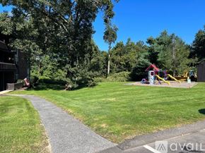 Seymour condo for rent - A playground with a slide and swings is surrounded by trees and grass.