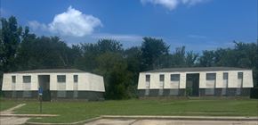 Bude apartment for rent - Two identical buildings are situated in a grassy field.
