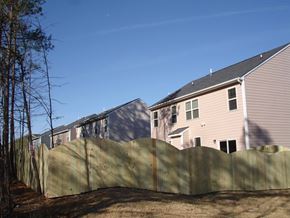 Durham house for rent - A wooden fence separates a grassy area from a row of houses.