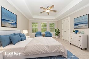 Antioch house for rent - A bedroom with a large bed, a ceiling fan, and two paintings on the wall.